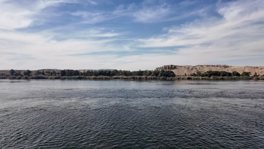 Overhead aerial drone view of traditional Egyptian felucca sailboat on Nile River Aswan Egypt with blue water and peaceful landscape 4K 60fps