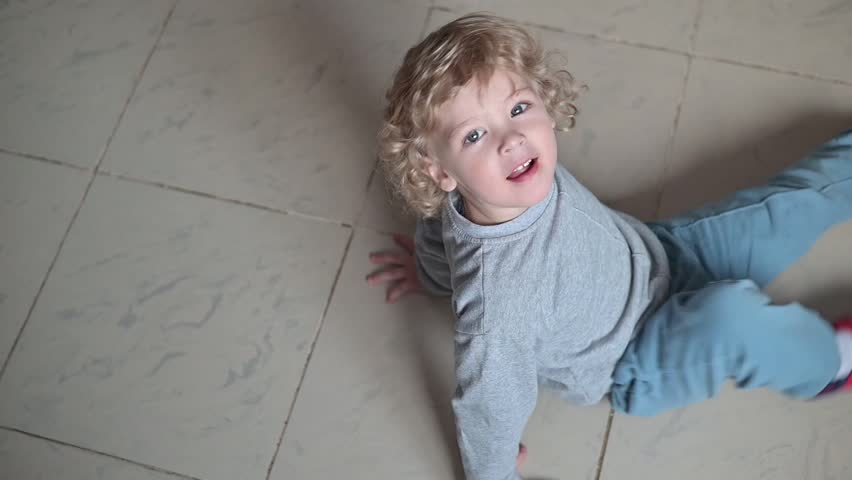 Child engages in playful activity on the floor, rolling and moving in different directions. The action showcases developmental milestones and playtime behavior.