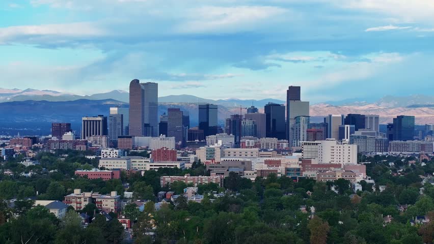 Aerial establishing of downtown Denver skyline with mountains beyond, medium ascend