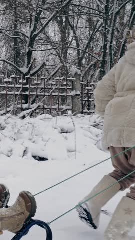 Family sledding in winter. outdoor winter activity. Happy, laughing, playful children are enjoying of sledging on snowy road, in forest, during snowfall. kids are having fun on snowy winter day
