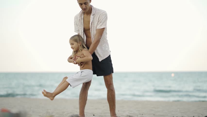 Joyful dad and child bonding on the beach, creating unforgettable memories during a warm evening. Playful outdoor activity highlights love, happiness, and the beauty of parenthood