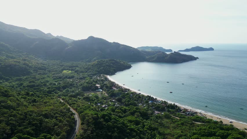 Wide daytime summit panorama showcasing dramatic rock monolith, blue skies, and lush coastal mountains at Pico De Loro Nasugbo Batangas Philippines