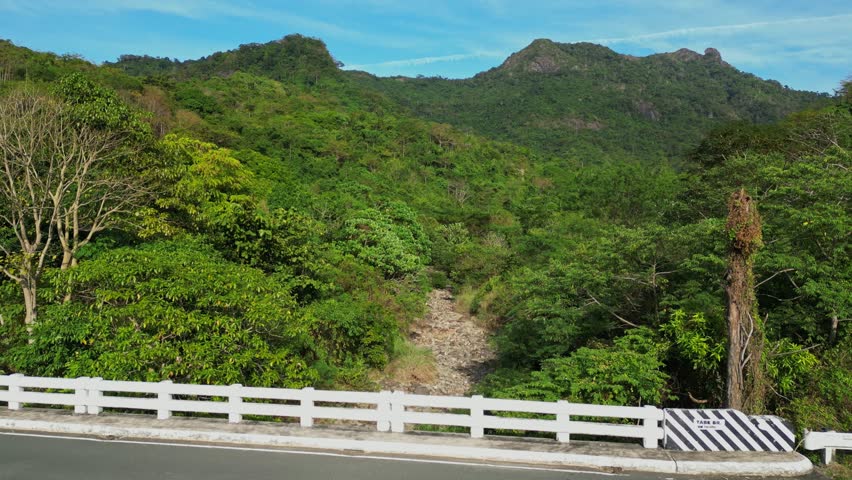 Side ridge composition capturing iconic monolith and rolling mountains during bright daytime conditions at Mt Pico De Loro Nasugbo Batangas Philippines
