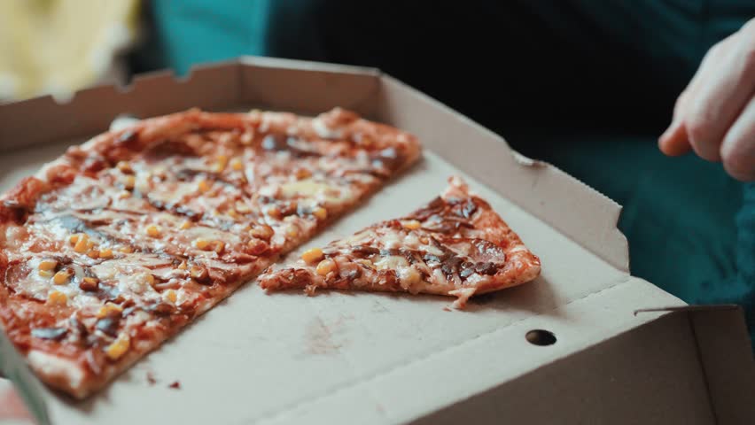 Close up of male hands taking a hot pepperoni pizza slice from a delivery box.