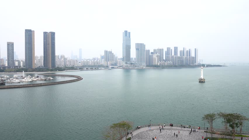 Panoramic view of Haikou city skyline with modern skyscrapers, waterfront promenade, and lighthouse