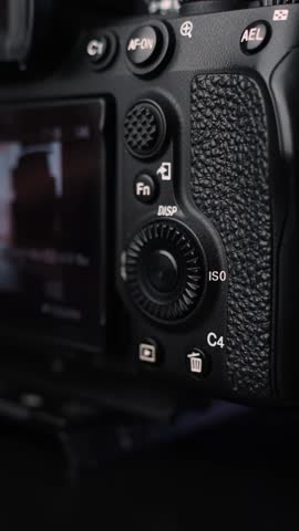 Close-up of hand using rear control wheel to browse image playback on digital camera screen, showcasing photo review workflow in studio lighting.