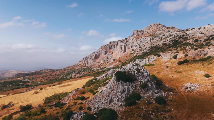 Rocky mountain slope with grasslands and clouds