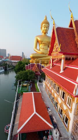 Cinematic FPV drone fly around giant golden Buddha at Wat Paknam temple in Bangkok, Thailand. Aerial movement over city skyline and Buddhist landmark.