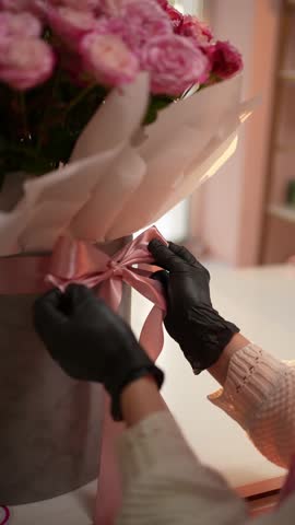 Florist tying a satin ribbon on a flower box. The concept of creating a bouquet.