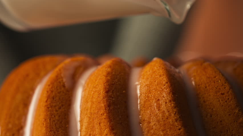 White Glaze Being Poured Over Golden-brown Bundt Cake - Easter Food. closeup shot