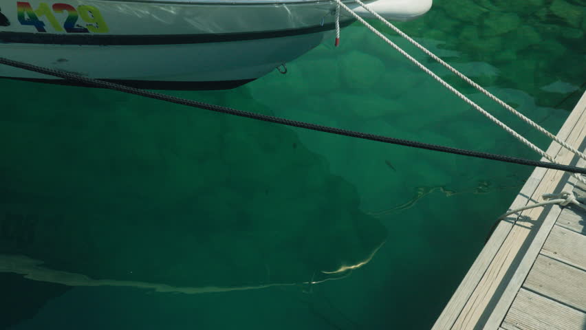 Tranquil Maritime Scene. Serene Boat Dock By Water. Peaceful Harbor With Shimmering Water Surface. Calm Seaside Setting With Glassy Water And Dock Structures Visible