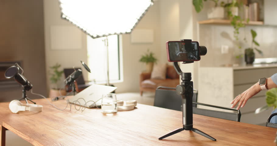 Entering African American woman sitting at home table speaking into microphones and showing laptop. Studio, content creation, modern decor, technology, broadcasting, entertainment, lifestyle