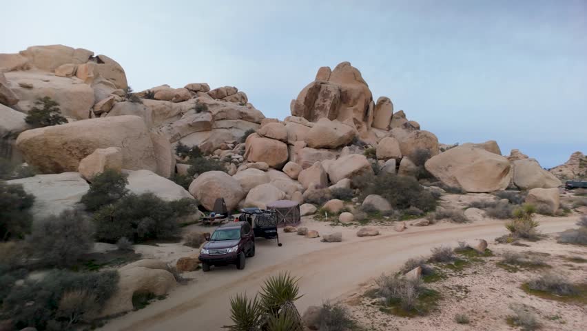 A teardrop camper trailer travels through Joshua Tree National Park exploring the desert landscape while biking along the trails