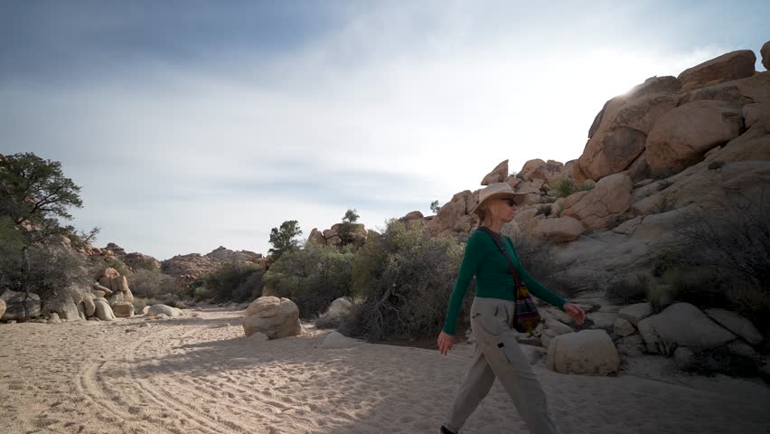 A woman explores the Willow Hole trail in Joshua Tree National Park in California surrounded by unique rock formations and desert landscape