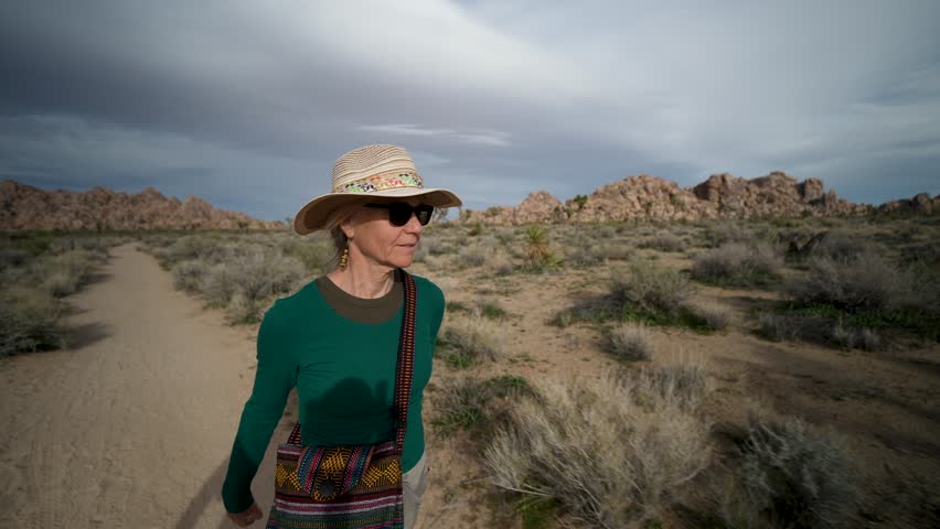 A senior woman hikes the Willow Hole trail in Joshua Tree National Park in California enjoying the beauty of the desert landscape.
