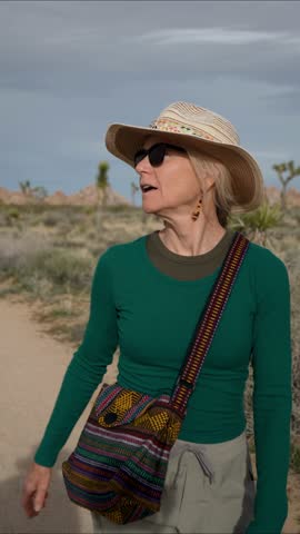 Mature woman hikes along the Willow Hole trail in Joshua Tree National Park while enjoying the desert landscape and sunshine.