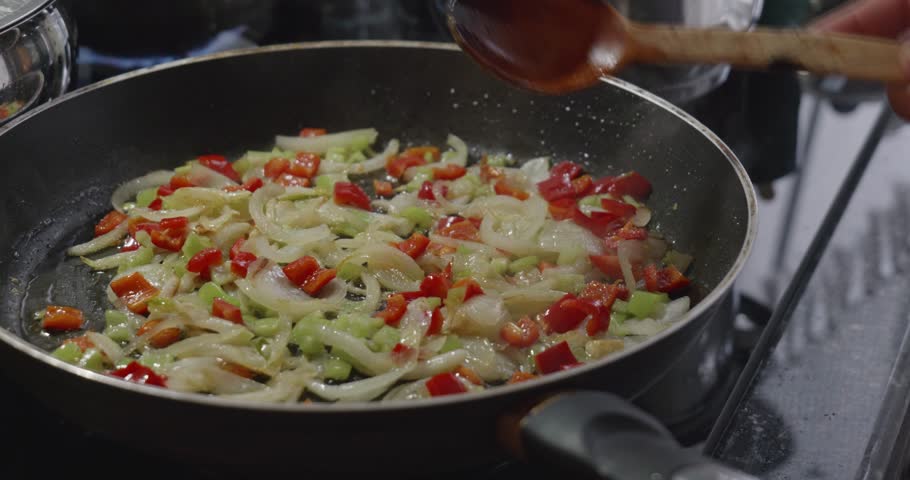 Sauteing Onions and Peppers with Wooden Spoon in Pan