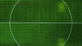This video captures an aerial perspective of a rectangular football pitch. The visual documents green turf with vertical mowing patterns and white painted markings, including the center circle and penalty areas. The composition illustrates a stadium environment with goalposts and a spectator stand, documenting athletic infrastructure and field layout in a high-resolution 4K format for sports and urban media. - Powered by Shutterstock - Get 15% off with code: PIKWIZARD15