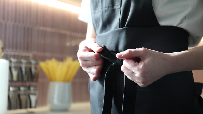 Woman tying clean apron at home, closeup
