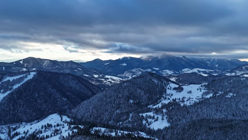 Aerial hyperlapse of dramatic clouds moving over winter mountain peaks and snowy forest