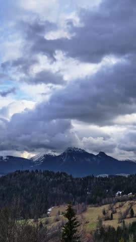 Vertical timelapse of dramatic storm clouds moving over snowy mountain peaks
