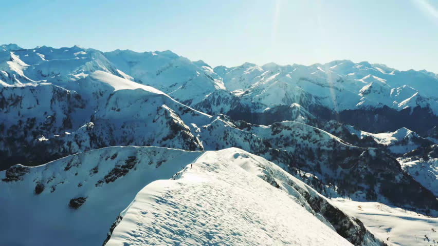 A breathtaking view of a snowy mountain range illuminated by bright sunlight, showcasing the peaks and valleys covered in snow.