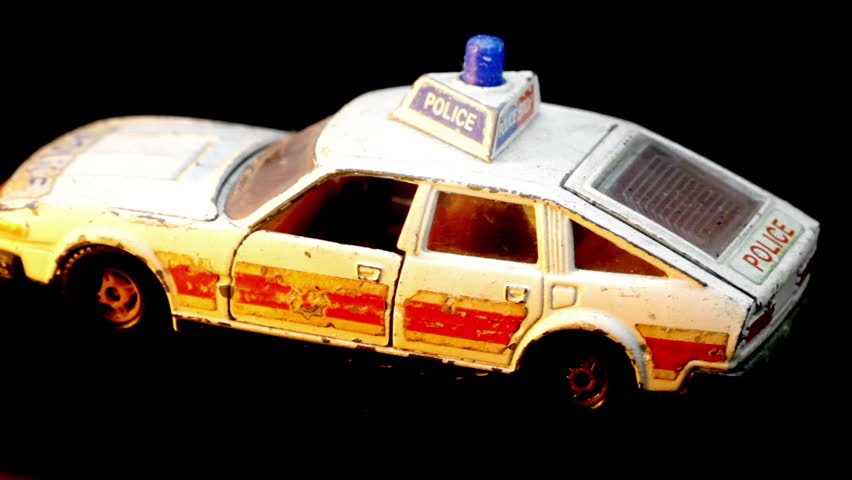 retro toy police car spinning isolated on black 