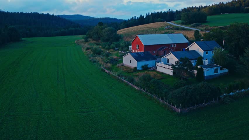 A House And A Barn Along Greenery Fields And Mountains. Aerial Shot