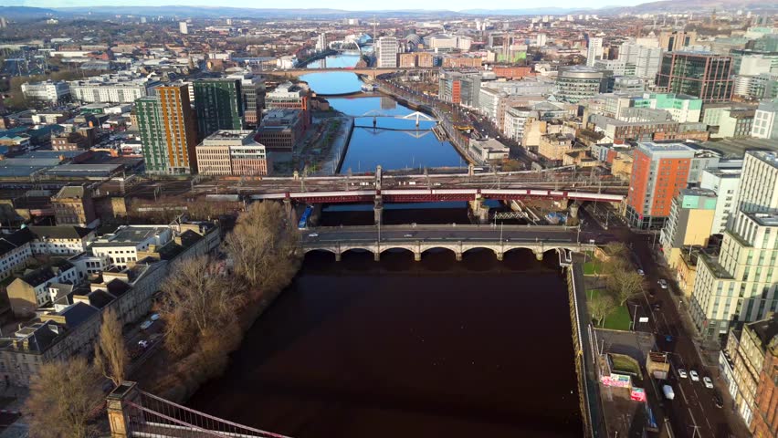 Glasgow Scotland: 13th Feb 2026: Bridges (Caledonian Railway Bridge, King George V Bridge, Glasgow Bridge) over River Clyde. Drone view golden hour with city skyline. Panning shot