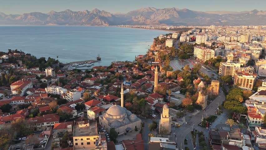 Sunset aerial view of Antalya old town with historic mosques and clock tower, beautiful cityscape of Kaleici district against Taurus mountains. Beautiful Turkish city of Antalya at sunset