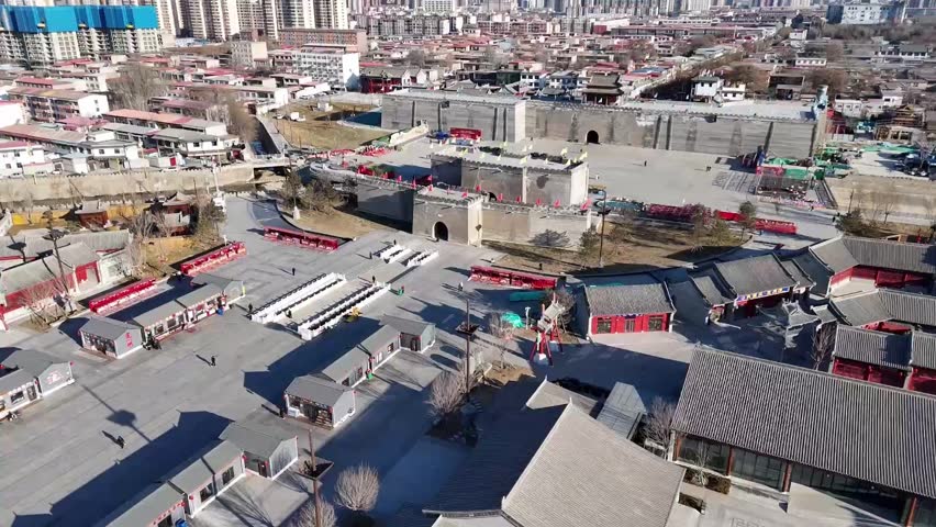 A steady 1080p aerial static shot overlooking the majestic ancient city wall, gatehouse, and a large public square in Zhengding, Hebei province. The scene captures the blend of historical preservation and modern urban tourism.