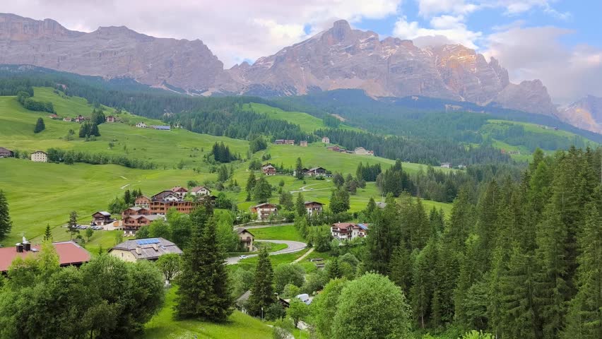Scenic view of winding mountain road and alpine landscape in Alta Badia, La Villa, Dolomites, Italy. Green meadows, forests and dramatic peaks create a calm natural atmosphere in the Italian Alps.
