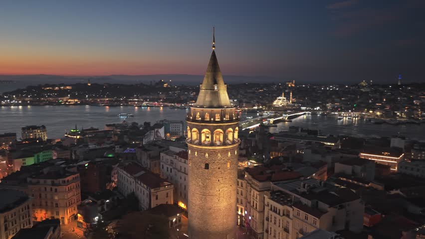 Aerial view of the illuminated Galata Tower at sunrise in Istanbul, Turkey. Cinematic drone orbit around the Galata Tower at twilight in Istanbul Turkey. Beautiful cityscape of Beyoglu district