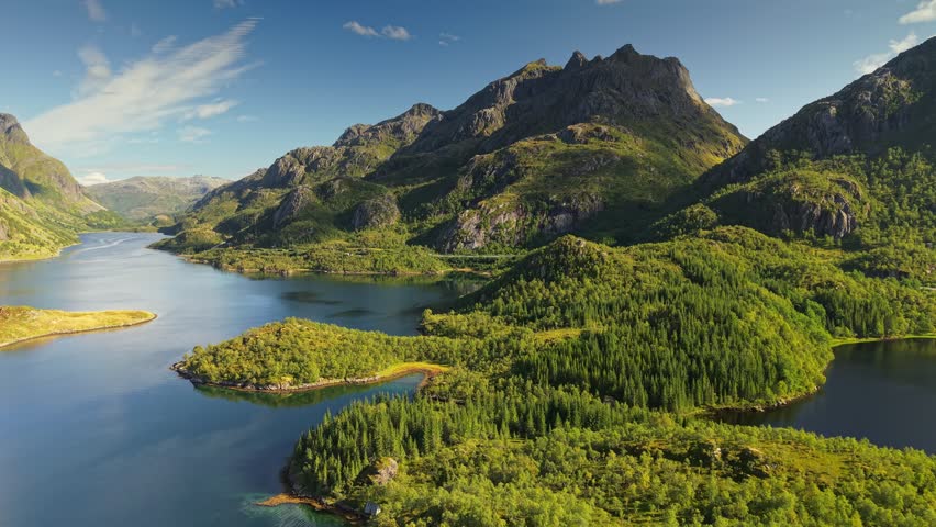 Stunning aerial panorama of Lofoten islands in Norway, majestic green mountains and deep blue fjords under sunny sky. Beautiful nature of Lofoten islands with lush green woods and rocky peaks