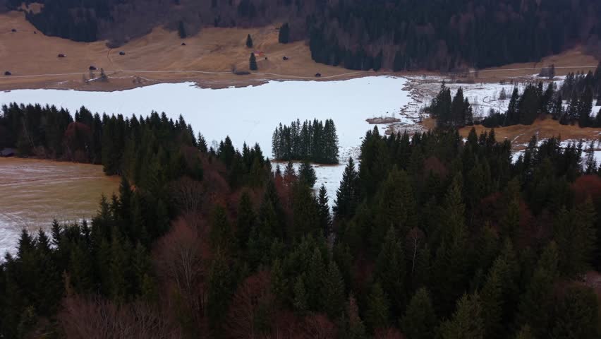 Stunning aerial of snowy Geroldsee Wagenbruchsee in Kruen Bavaria. A famous winter travel spot in the German Alps. Tranquil nature footage of a popular mountain lake.