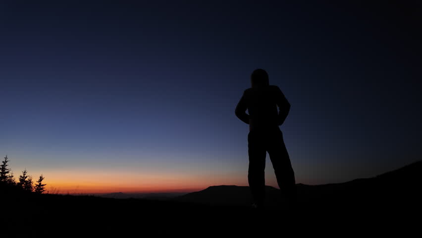 Man with smartphone photographing and observing mountain landscape in dawn - dusk - twilight.