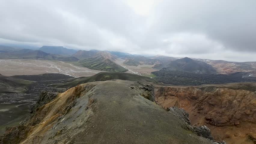 Aerial panoramic view of the colorful rhyolite mountains, volcanic landscape and lake in Landmannalaugar, Iceland. Dramatic highland scenery with green hills, lava fields and winding road in the Icelandic Highlands, popular destination for hiking and adventure travel.