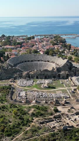 Aerial view of the ancient city of side, turkey, showing the large roman amphitheater, agora, and the mediterranean sea in the background