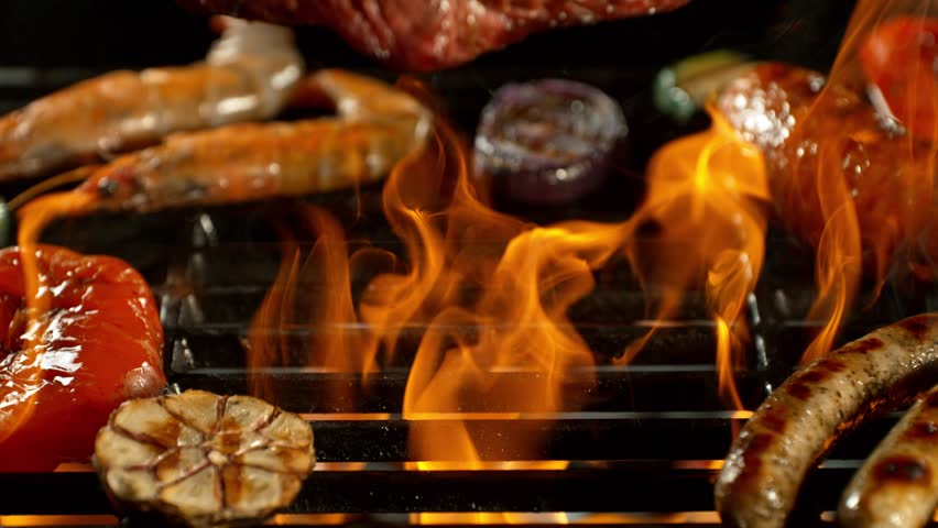 Slow Motion of Various BBQ Meat on a Grill with Roaring Flames . Camera Movement , Filmed on High Speed Cinematic Camera at 1000 FPS .