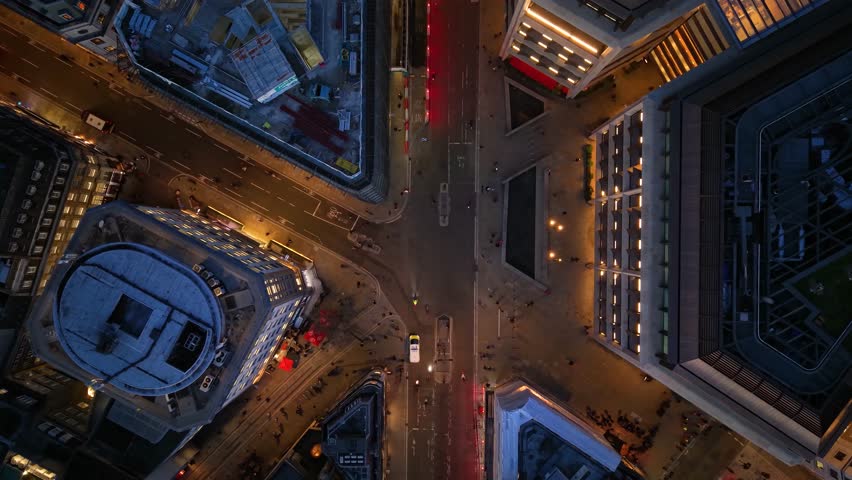Aerial overhead view of the illuminated streets at the City of London, England, during dusk with car and pedestrian traffic