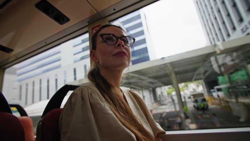 Tourist woman sitting on seat in Singapore city bus looking outside window, urban travel and transportation concept in Asia