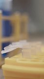 Vertical video macro of micropipette dispensing blue liquid sample into microtube in laboratory rack - Powered by Shutterstock - Get 15% off with code: PIKWIZARD15