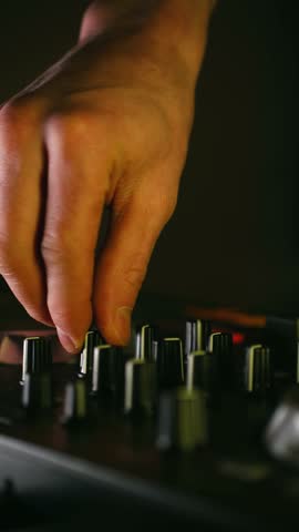 Professional dj hands skillfully manipulating controls on sound mixer board during live performance adjusting audio levels, creating electronic music in dimly lit nightclub. Vertical. Dj playing music