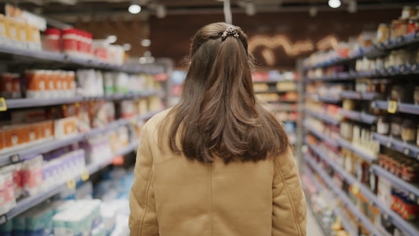 Woman shopping in supermarket aisle, customer choosing products in grocery store