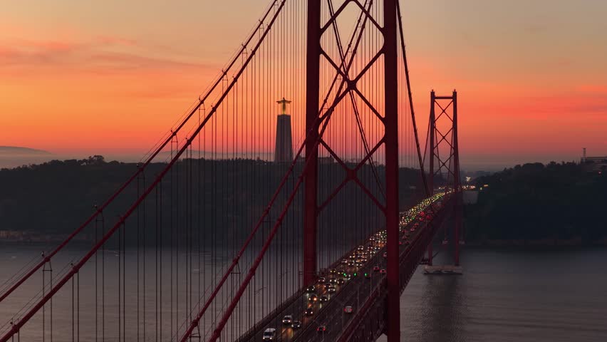 Sunrise in Lisbon, capital of Portugal. Sunrise at the bridge the 25 of April in the centre of Lisbon, Famous Cristo Rei statue with the bridge 25 de Abril establishing shot. 