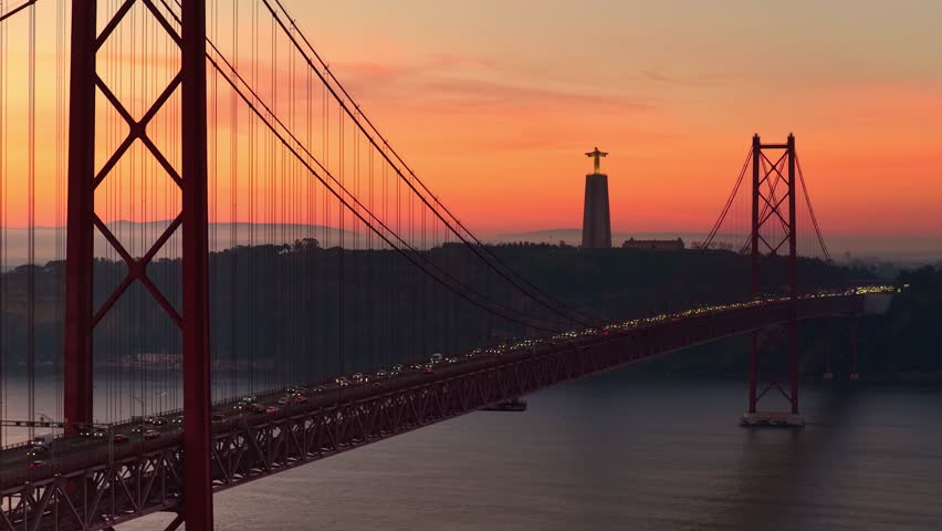 Morning drone view of Lisbon, capital of Portugal. Sunrise at the bridge the 25 of April in the centre of Lisbon, Famous Cristo Rei statue with the bridge 25 de Abril establishing shot. 