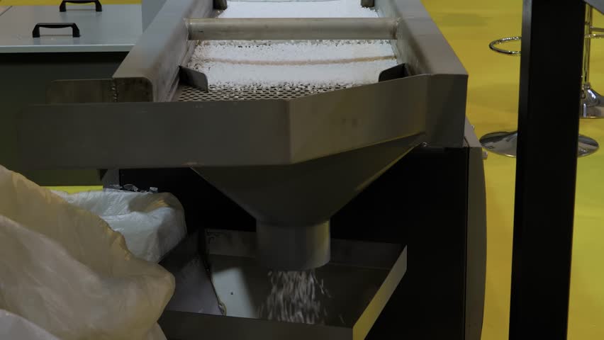 Propylene or polyethylene pellets - recycled plastic granules on conveyor belt, shale shaker of waste plastic recycling machine. Environmental protection, separation, automated technology concept