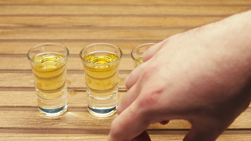 Mexican Tequila Mezcal pouring with lime and salt on a stone table. Strong vodka rum alcoholic drink is poured from a bottle into a shots.