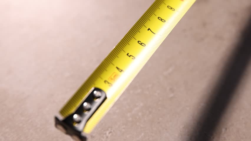 One measuring tape on grey table, above view. Camera moving up