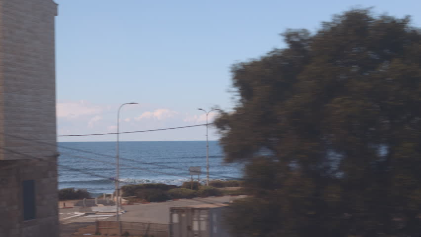 A view of the sea from a train window. Traveling through Israel by train. Train between Haifa and Tel Aviv. Travel and adventure in Israel.